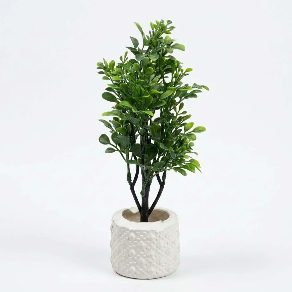 Mini artificial green plant in white ceramic pot